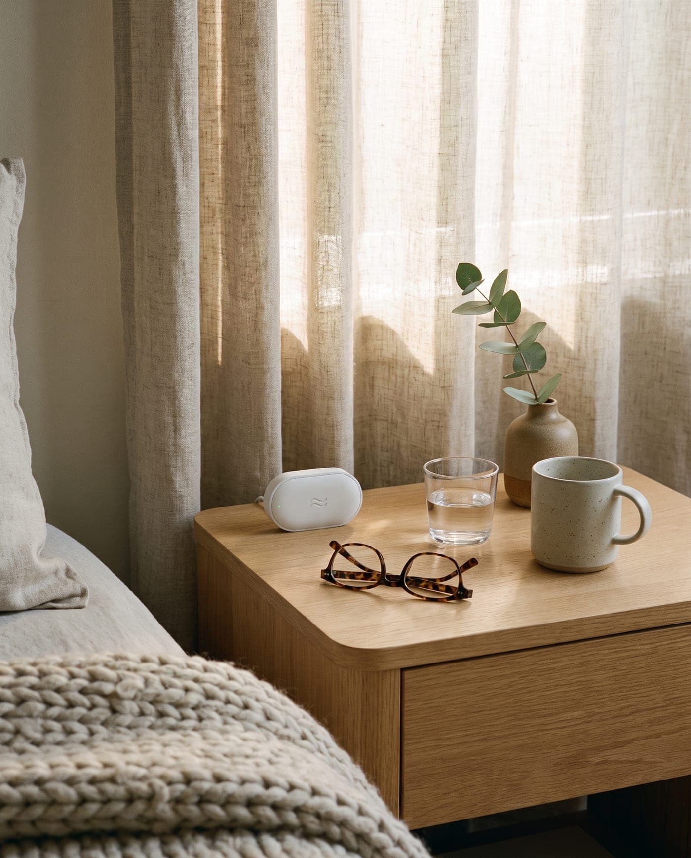 A quiet bedside table in the early morning light, with a small Kin sensor at the back